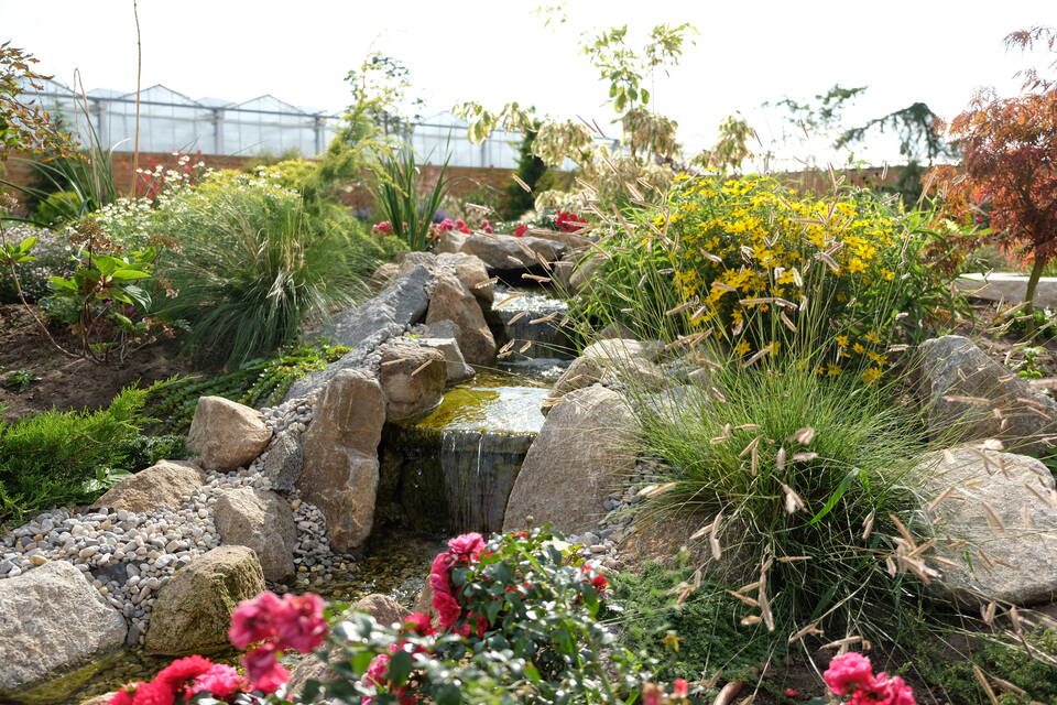 Mit Natursteinen umgebener Bachlauf im Garten mit Wasserfällen und Natursteinen.