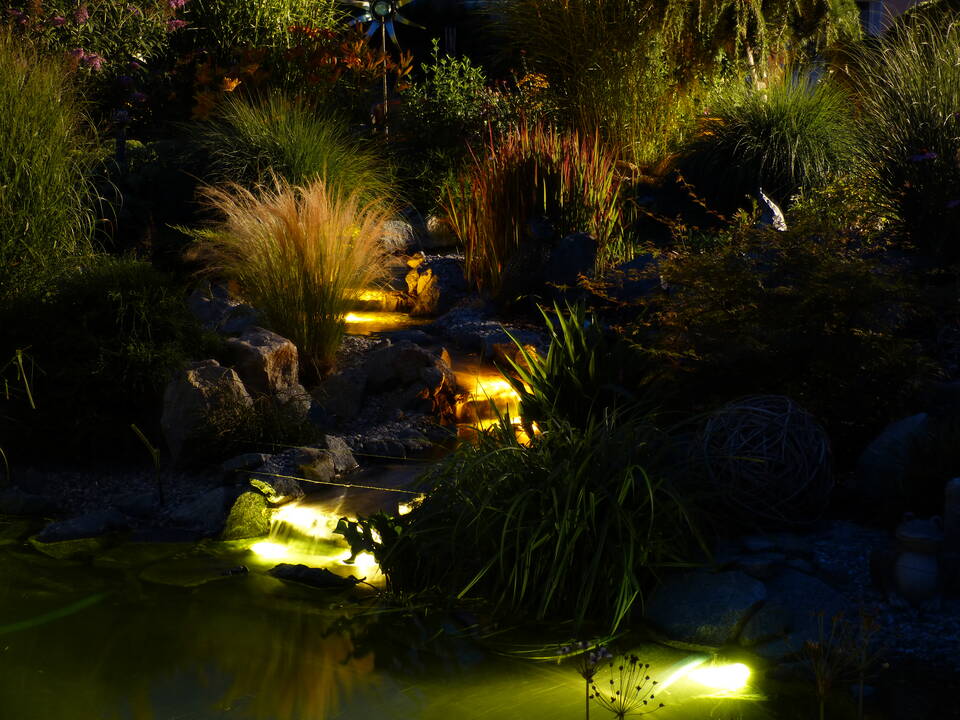 Bachlauf im Garten bei Dunkelheit mit beleuchteten Garten-Wasserfällen