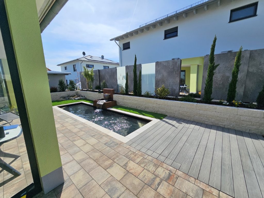 Sichtschutz-Zaun neben einem kleinen Pool, bestehend aus Beton-Platten, Milchglas und Spiegeln.