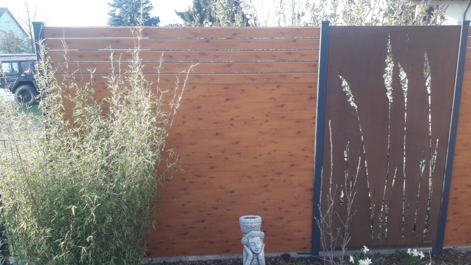 Sichtschutz-Zaun aus Holz mit Element aus Cortan-Stahl (Rost-Optik mit Schilf-Motiv)