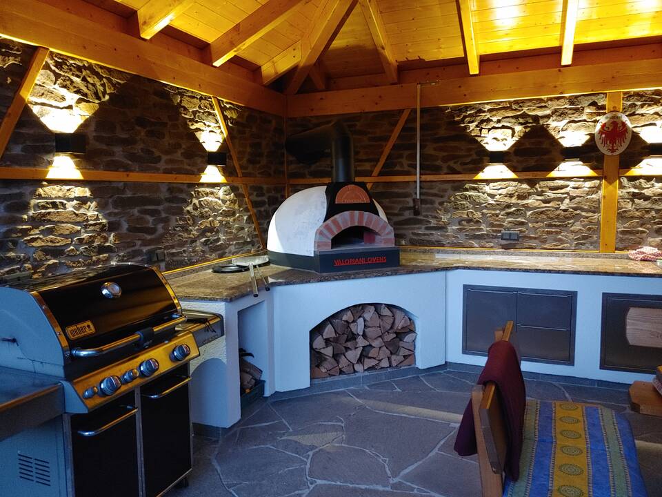 Gasgrill und gemauerter Pizza-Ofen in einer Außenküche mit Dach in Nürnberg