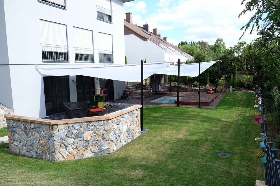 Gartengestaltung in Langenzenn: Terrasse mit Pool und Pooldeck, Sonnensegel, Outdoorküche; davor Rasen