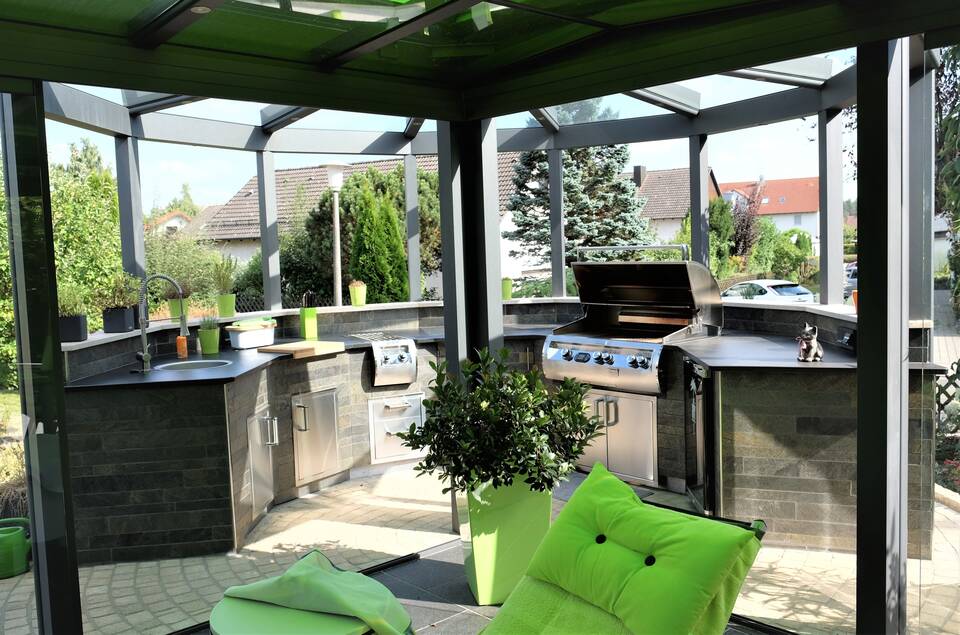 Aufgeklappter Gasgrill und Outdoor-Spüle in der gemauerten Gartenküche.