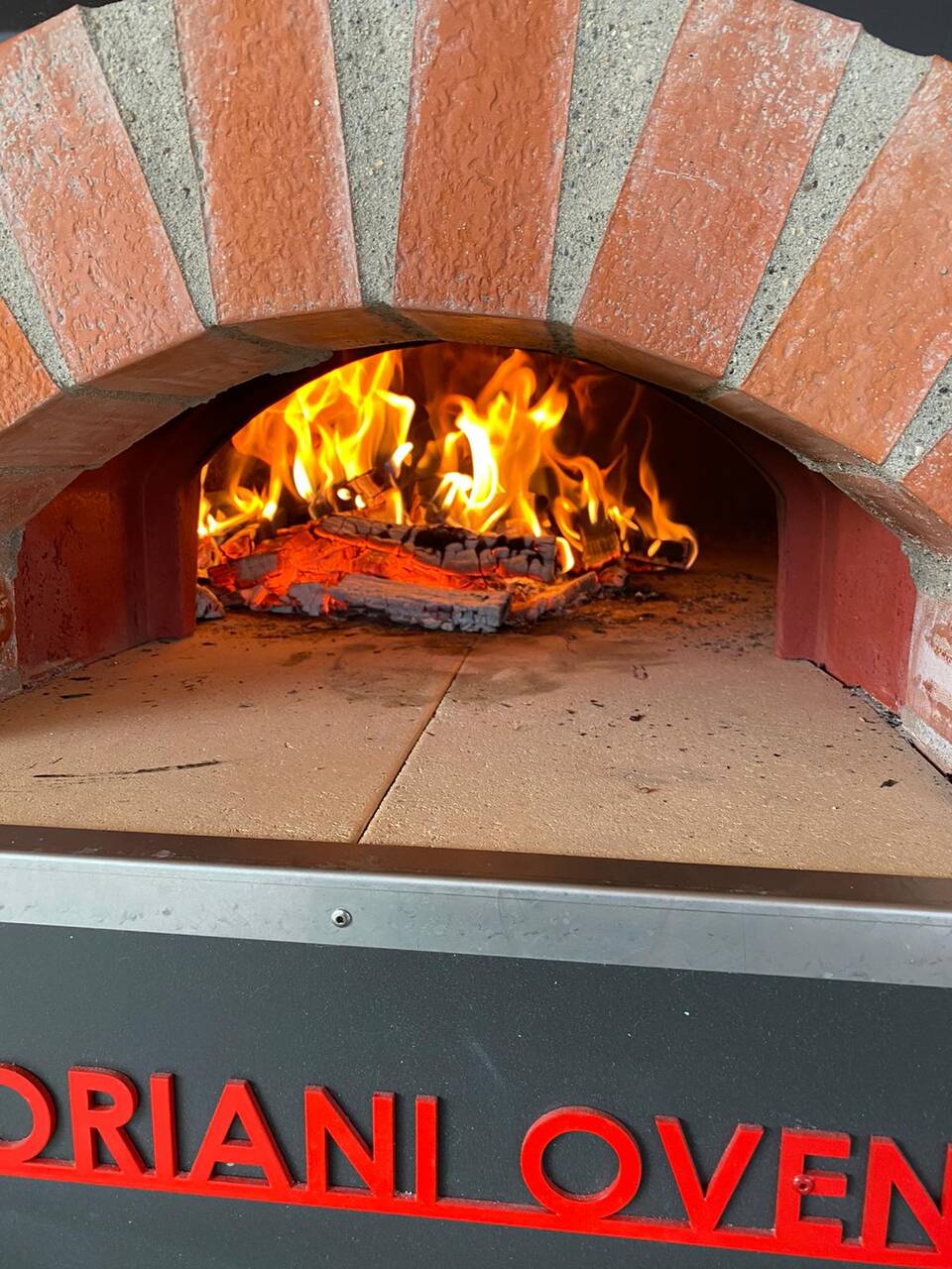 Holzfeuer im Pizzaofen einer Outdoor-Küche