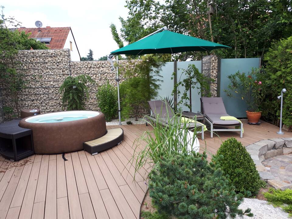 Whirlpool auf einer Holzterrasse mit Gartenliegen und Sonnenschirm bei Erlangen.