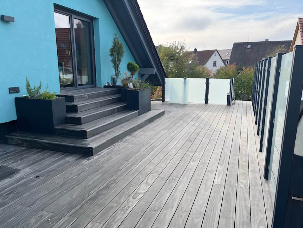 Sichtschutz und Absturzsicherung auf einer Dachterrasse bei Nürnberg, bestehend aus grau lackierten Stahl-Zaunpfählen und Glasscheiben aus Milchglas.