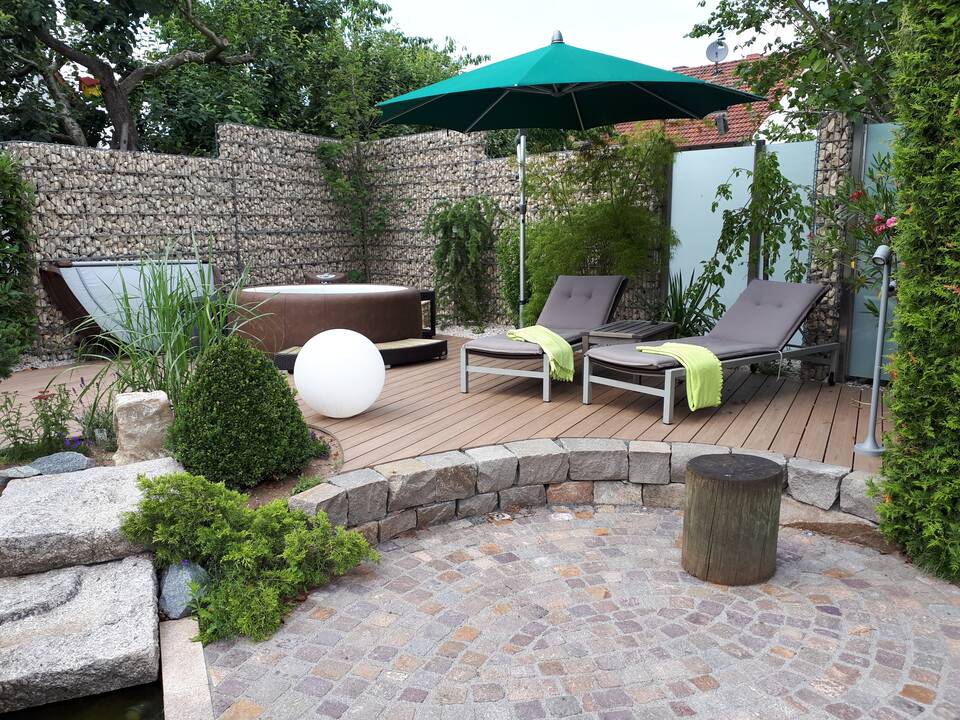 Sichtschutz-Wand als Gartenzaun bei Nürnberg: Die Gabionen werden von Zaun-Elementen aus Edelstahl und Milchglas unterbrochen.