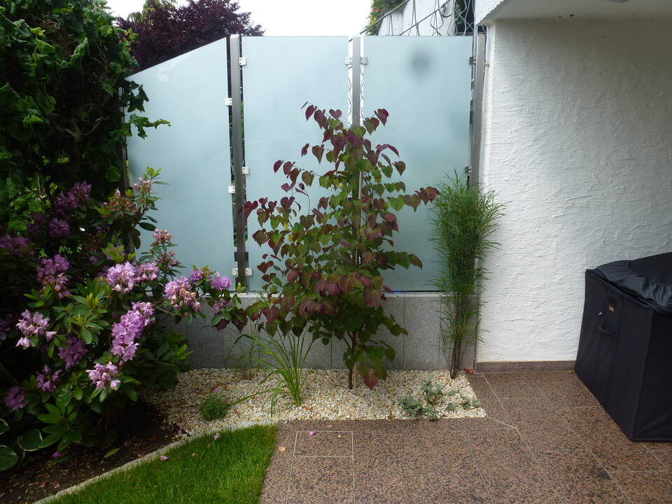 Edelstahl-Pfosten halten Milchglas-Scheiben als Terrassen-Sichtschutz zwischen 2 Reihenhäusern