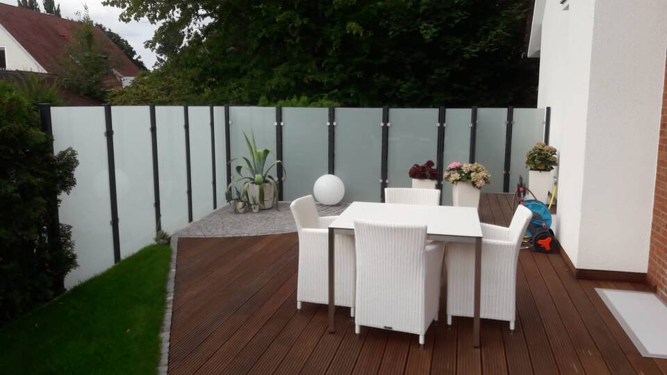 Dachterrasse mit Sichtschutz-Geländer aus Glasscheiben und schwarzen Alu-Trägern