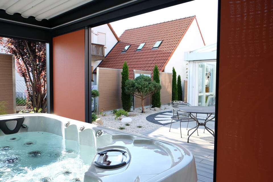 Sichtschutz-Zaun aus Aluminium-Profilen und holzfarbenen WPC-Platten, dazwischen Thuja-Hecke.