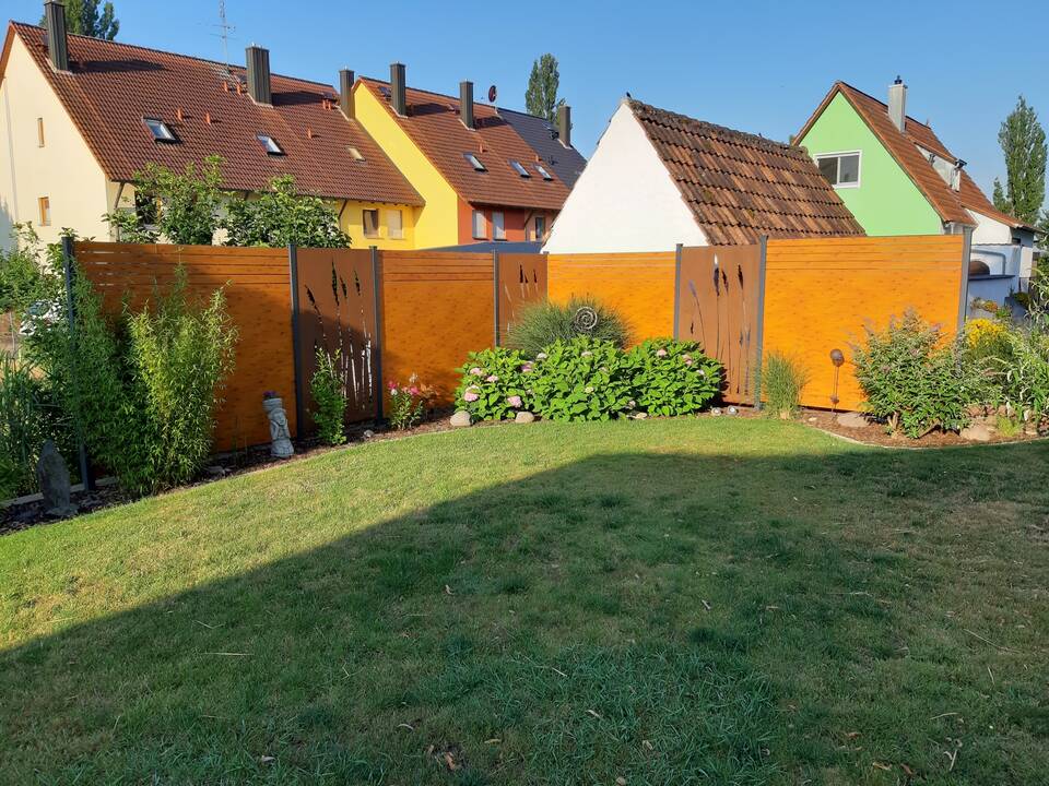 Sichtschutz-Zaun abwechselnd aus Holz und Cortenstahl mit ausgeschnittenem Schilf-Muster. Beispiel für Zaunbau in Nürnberg.