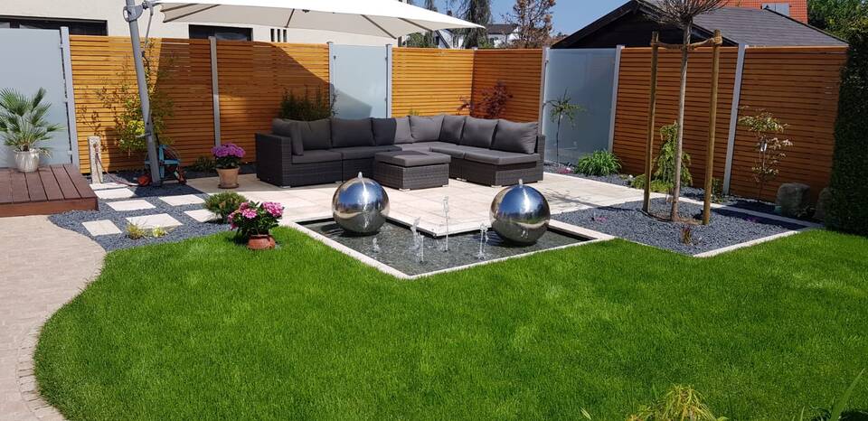 Sichtschutz-Zaun für eine Gartenlounge: Abwechselnd Holzwände und undurchsichtiges Glas.