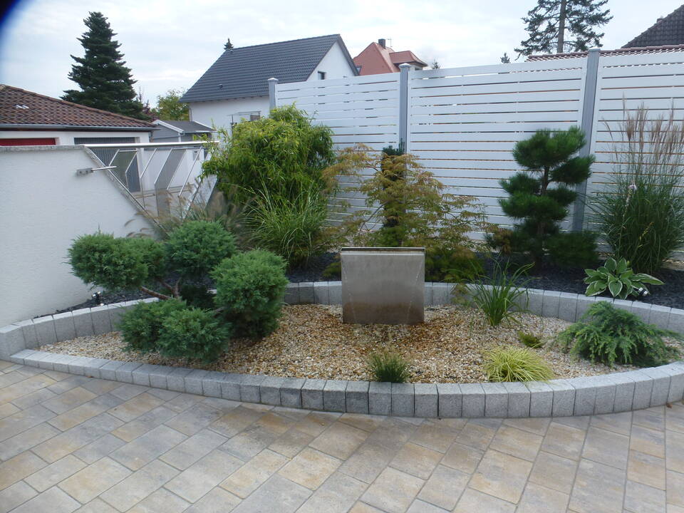 Weiße Sichtschutz-Wand mit Alu-Pfosten, daneben weiße Gartenmauer mit Glas-Element als Gartenzaun
